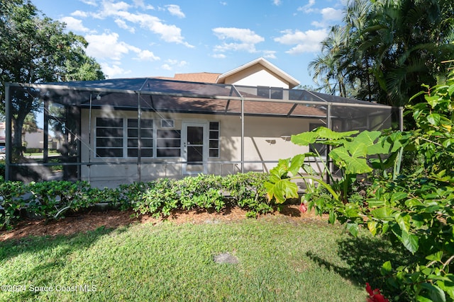 view of home's exterior with glass enclosure and a lawn