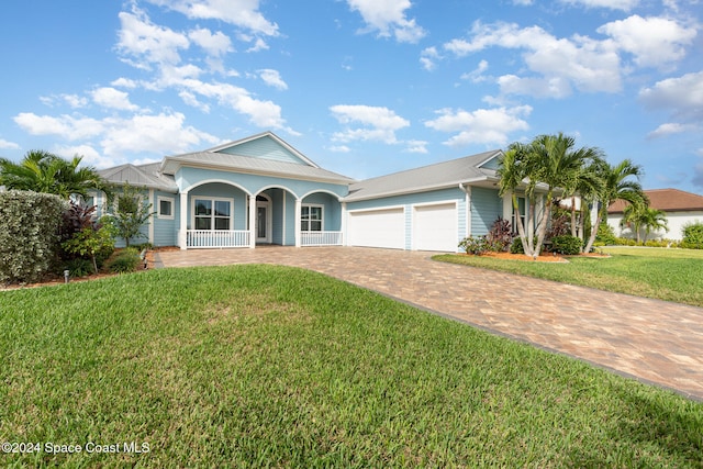 ranch-style house with a front lawn, covered porch, and a garage