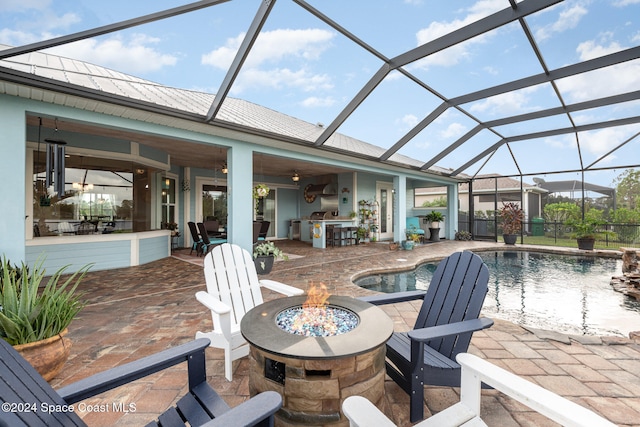 view of patio / terrace with glass enclosure, ceiling fan, and a fire pit