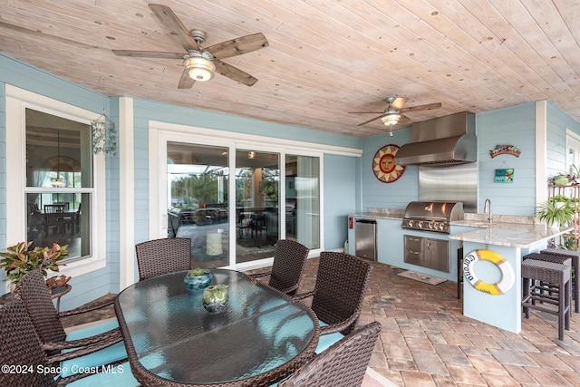 view of patio with area for grilling, a grill, ceiling fan, and a wet bar