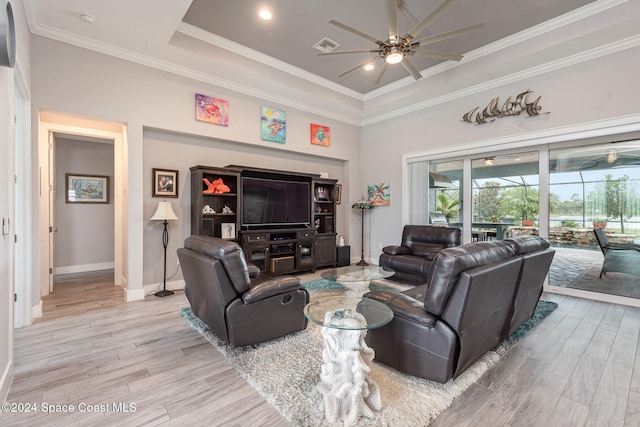 living room featuring a raised ceiling, ceiling fan, ornamental molding, a towering ceiling, and light hardwood / wood-style floors