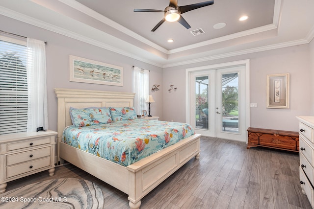 bedroom with access to exterior, dark hardwood / wood-style floors, a raised ceiling, and multiple windows