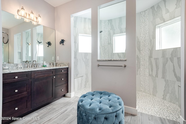 bathroom with hardwood / wood-style flooring, vanity, and a tile shower