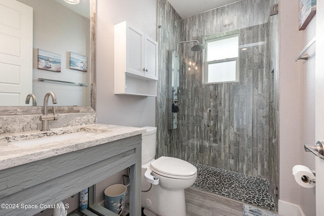 bathroom with vanity, hardwood / wood-style flooring, toilet, and a shower with shower door