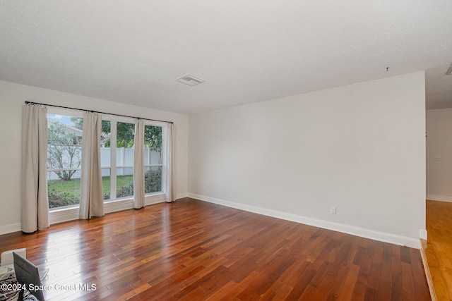 unfurnished room with hardwood / wood-style floors and a textured ceiling