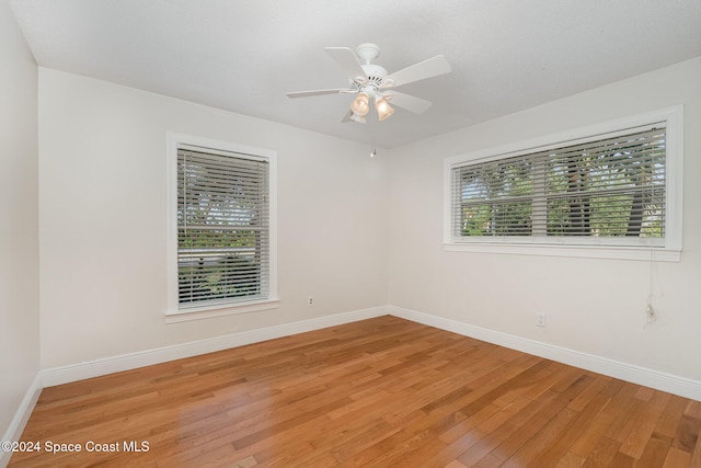 unfurnished room featuring ceiling fan, wood-type flooring, and plenty of natural light