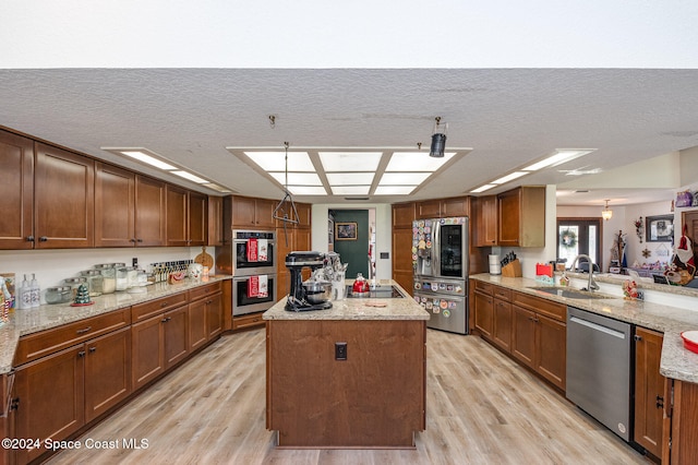 kitchen featuring appliances with stainless steel finishes, a center island, light hardwood / wood-style floors, and sink