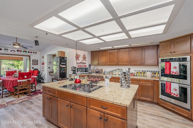 kitchen featuring ceiling fan, a center island, stainless steel double oven, and light wood-type flooring