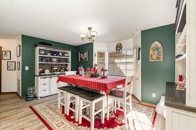 dining room with a chandelier, hardwood / wood-style floors, and a textured ceiling