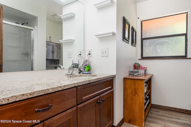 bathroom featuring hardwood / wood-style floors, vanity, and a shower with shower door