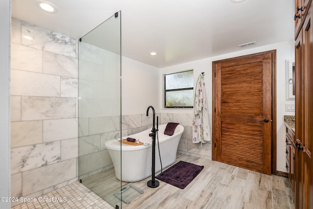 bathroom featuring a bathtub, vanity, wood-type flooring, and tile walls