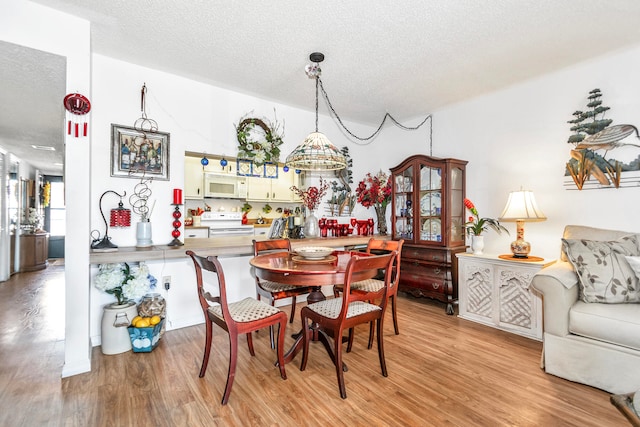 dining space with a textured ceiling, light hardwood / wood-style floors, and a chandelier