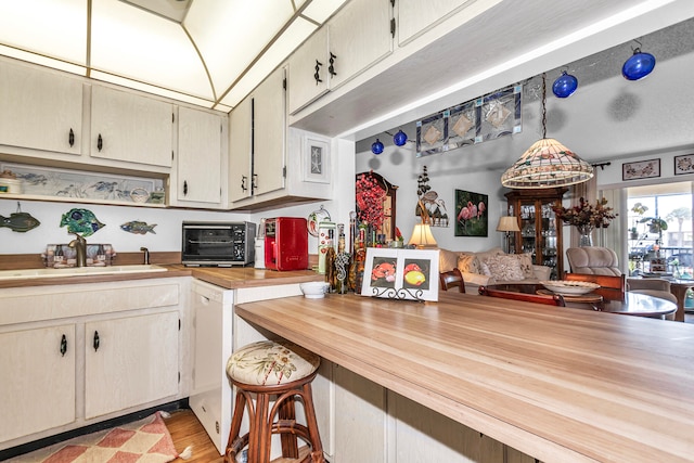 kitchen featuring light hardwood / wood-style flooring, butcher block counters, sink, and decorative light fixtures