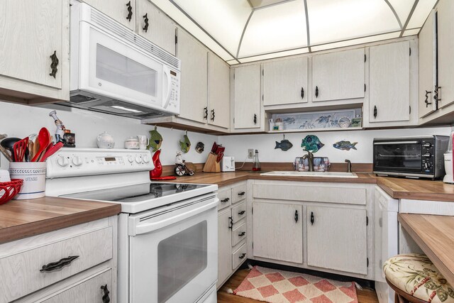 kitchen with white appliances, sink, light hardwood / wood-style floors, and wood counters