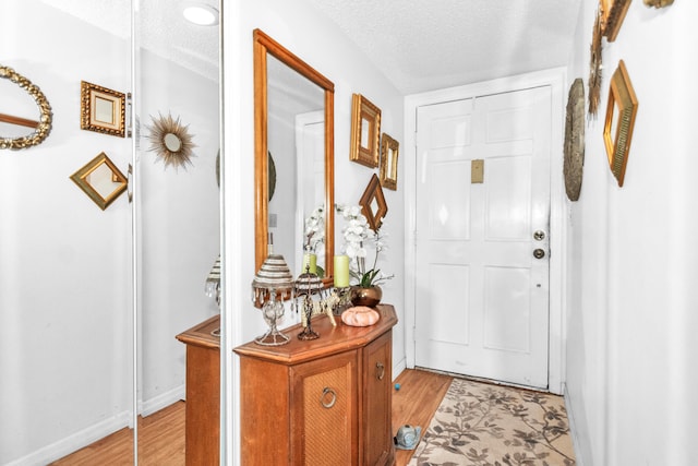 doorway to outside with light wood-type flooring and a textured ceiling