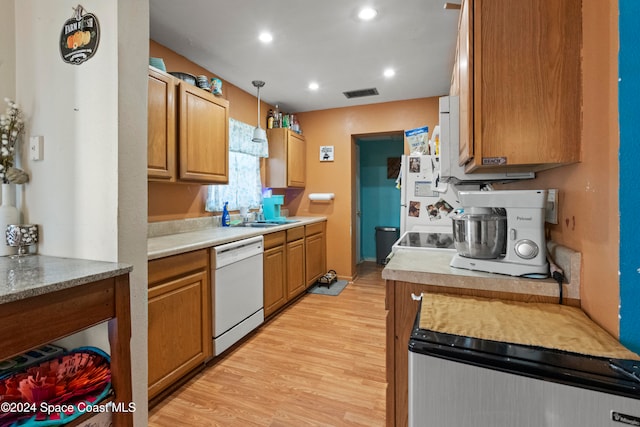 kitchen featuring decorative light fixtures, light hardwood / wood-style floors, white appliances, and sink