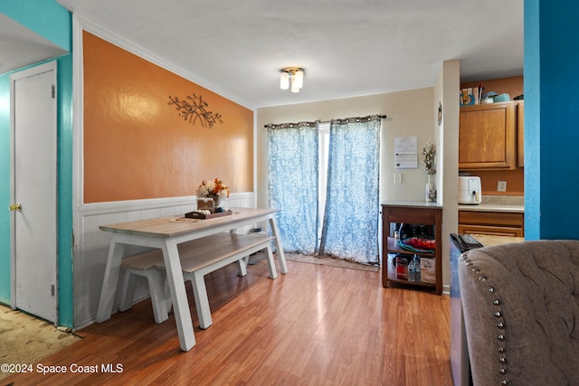 dining space with light hardwood / wood-style flooring and ornamental molding