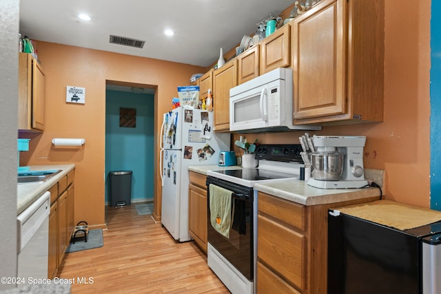 kitchen with light wood-type flooring, white appliances, and sink