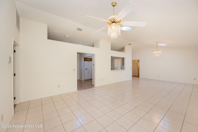 tiled empty room featuring ceiling fan with notable chandelier and vaulted ceiling