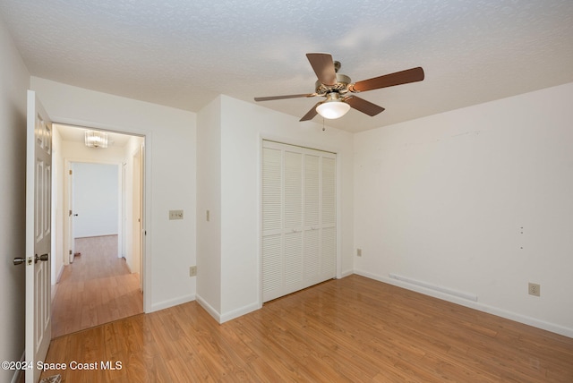 unfurnished bedroom featuring a textured ceiling, a closet, ceiling fan, and light wood-type flooring