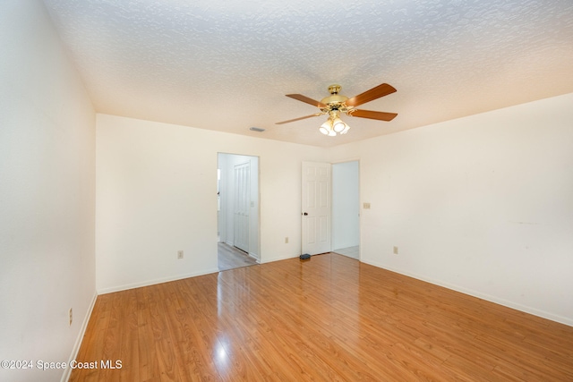 empty room with ceiling fan, a textured ceiling, and light wood-type flooring