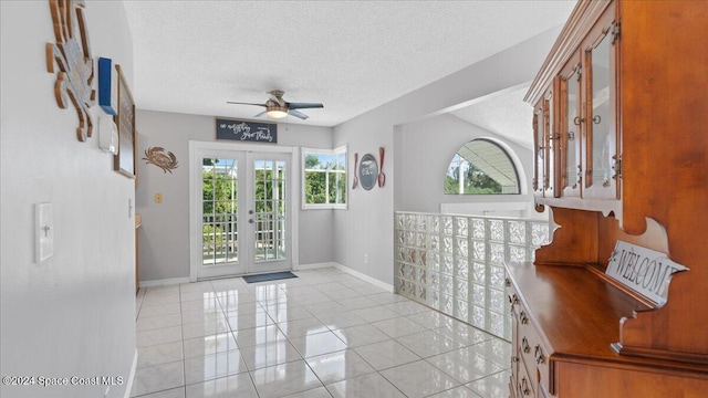 tiled foyer featuring french doors, a textured ceiling, and ceiling fan