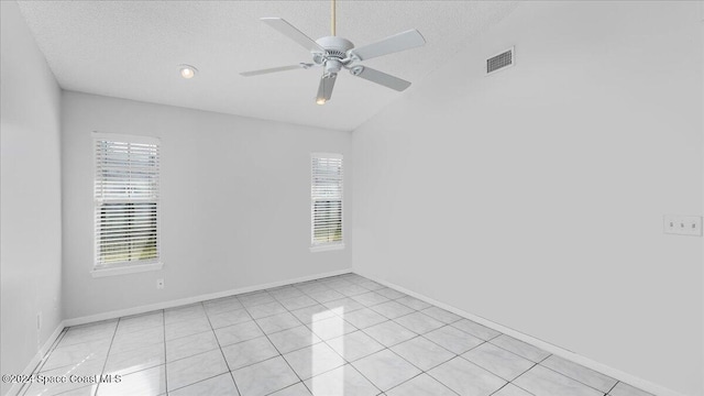 tiled empty room featuring ceiling fan, plenty of natural light, a textured ceiling, and lofted ceiling