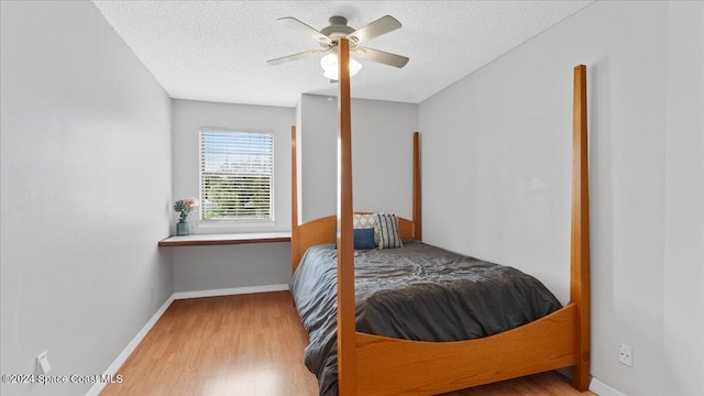 bedroom with light hardwood / wood-style floors, ceiling fan, and a textured ceiling