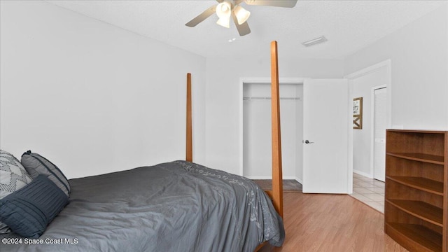 bedroom with a textured ceiling, light hardwood / wood-style flooring, ceiling fan, and a closet