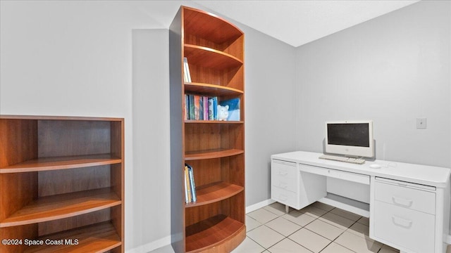 unfurnished office featuring built in desk and light tile patterned floors