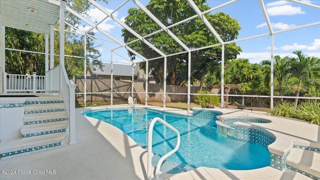 view of pool featuring glass enclosure, a patio, and an in ground hot tub