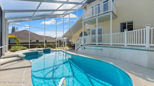 view of pool featuring a patio, glass enclosure, and an in ground hot tub