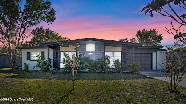 view of front of property with a garage and a lawn