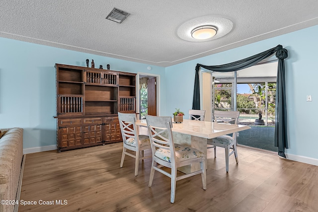 dining area with a textured ceiling and light wood-type flooring