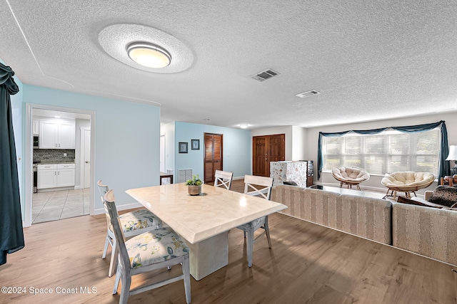 dining space featuring a textured ceiling and light hardwood / wood-style floors