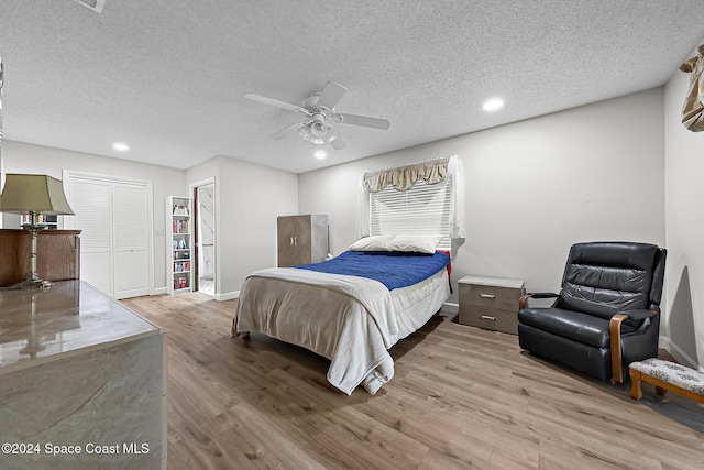 bedroom featuring ceiling fan, light hardwood / wood-style floors, and a textured ceiling