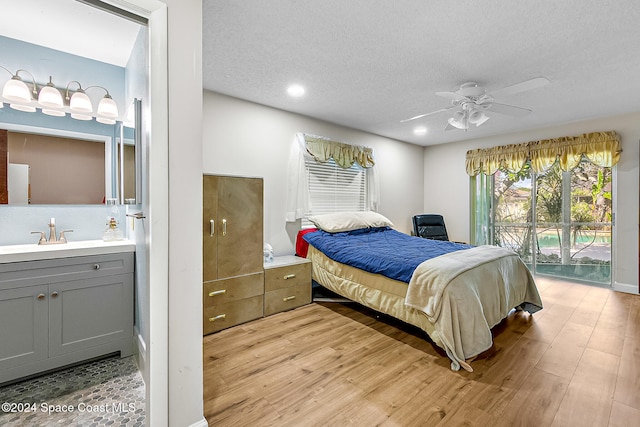 bedroom featuring sink, light hardwood / wood-style flooring, ceiling fan, access to exterior, and a textured ceiling