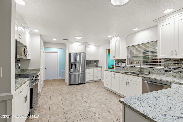 kitchen with white cabinets, sink, decorative backsplash, light stone countertops, and appliances with stainless steel finishes