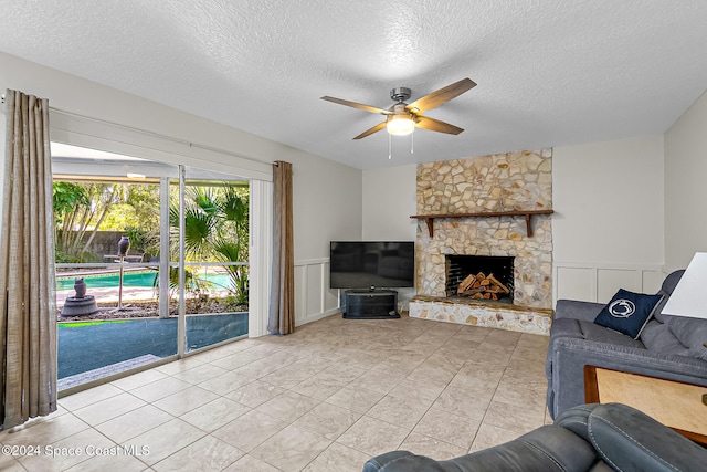 tiled living room with ceiling fan, a fireplace, and a textured ceiling