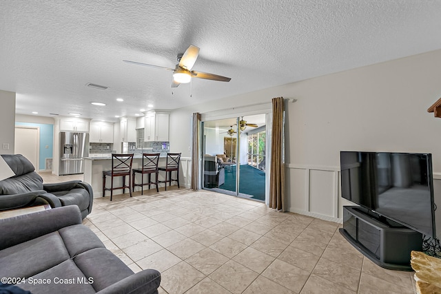 tiled living room featuring ceiling fan and a textured ceiling