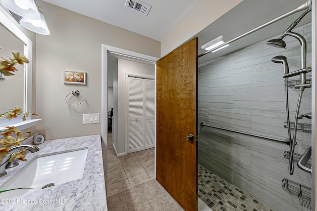 bathroom with a tile shower, tile patterned flooring, and vanity