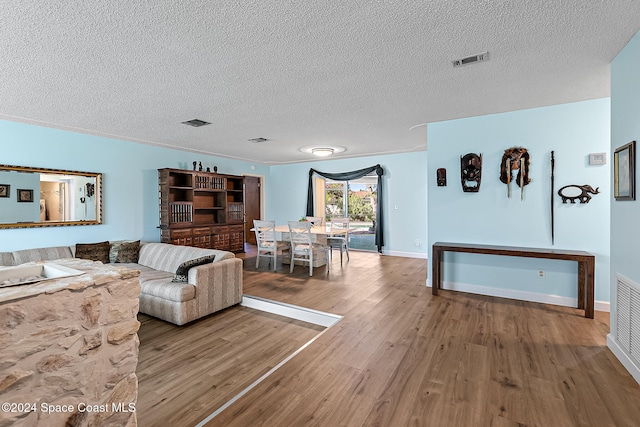 living room with hardwood / wood-style floors, a textured ceiling, and ornamental molding