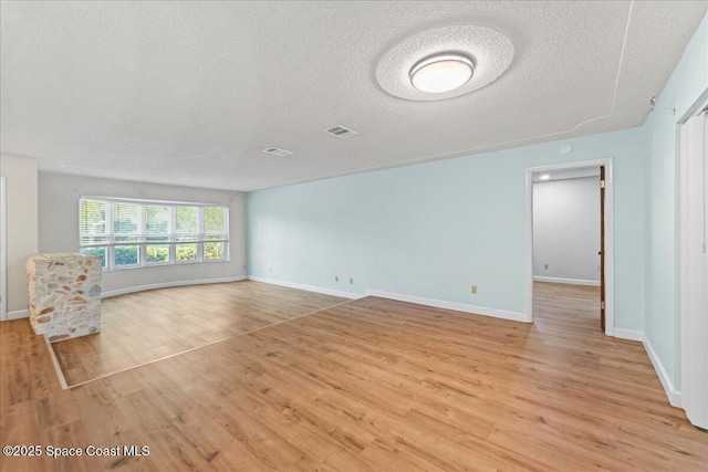 560 Rio Ln, Indialantic, FL 32903 - unfurnished living room with a textured ceiling, light wood-style floors, and baseboards