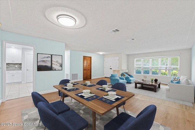 560 Rio Ln, Indialantic, FL 32903 - dining room featuring light wood-type flooring, baseboards, and a textured ceiling