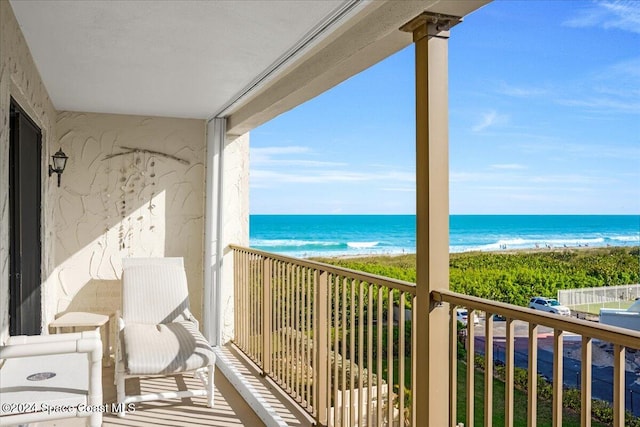 balcony featuring a view of the beach and a water view