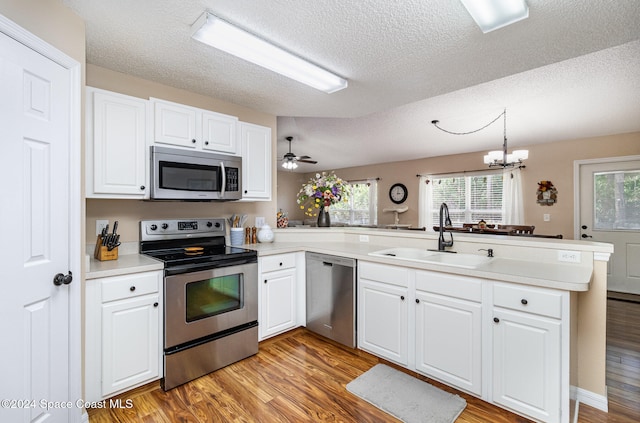 kitchen featuring plenty of natural light, light wood-type flooring, kitchen peninsula, and appliances with stainless steel finishes