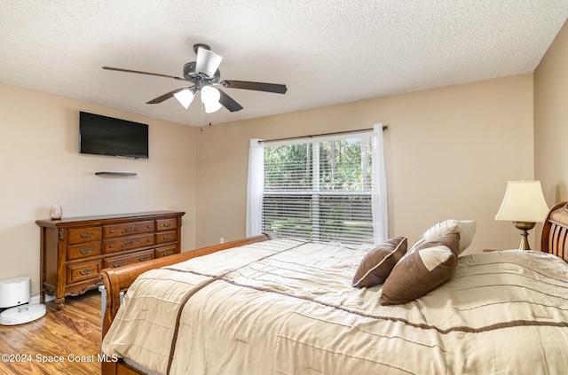 bedroom featuring ceiling fan, wood-type flooring, and a textured ceiling