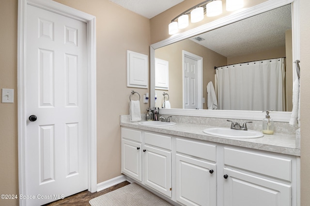 bathroom featuring vanity, wood-type flooring, and a textured ceiling