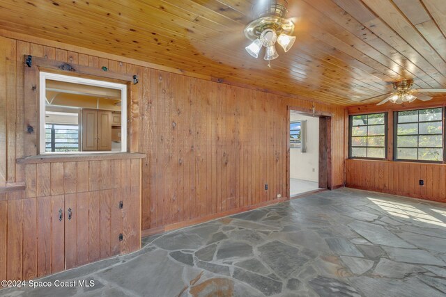 spare room featuring wooden walls, ceiling fan, and wooden ceiling