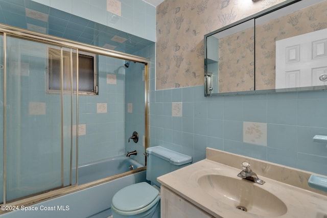 full bathroom featuring enclosed tub / shower combo, vanity, toilet, and tile walls